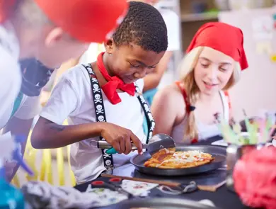 En gutt skjærer minipizza med pizzahjul 