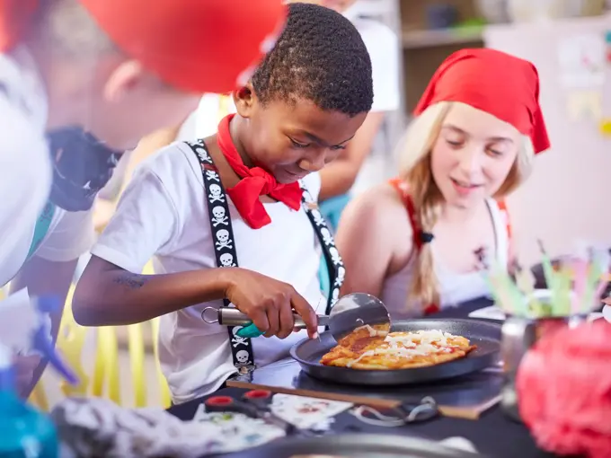 En gutt skjærer minipizza med pizzahjul 