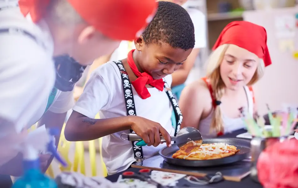 En gutt skjærer minipizza med pizzahjul 