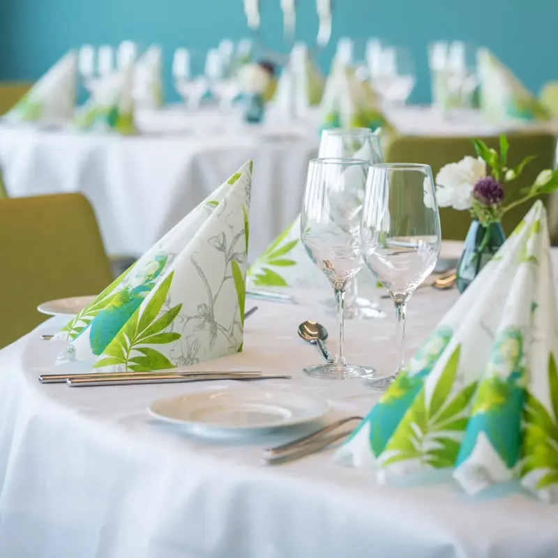 Dekkete bord med hvite duker og fargerike servietter i selskapslokale Lysefjord på Thon Hotel Maritim