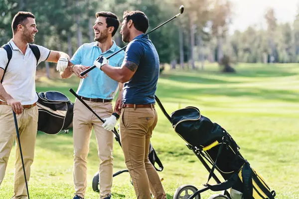 Multi-ethnic group of male golf players talking on the course playground
