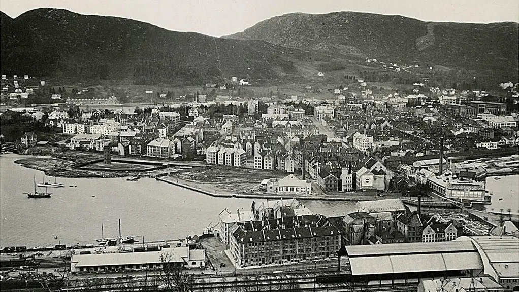 Svart-hvitt bilde av hus og begyggelse ved vannet