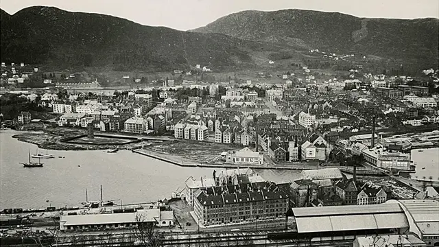 Svart-hvitt bilde av hus og begyggelse ved vannet