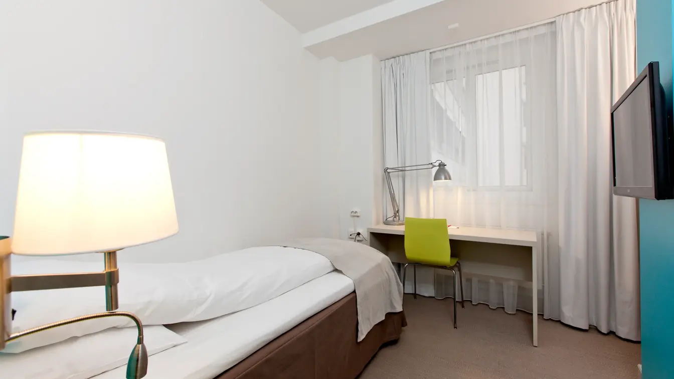 Seng, skrivebord og TV i enkeltrom på Thon Hotel Munch i Oslo