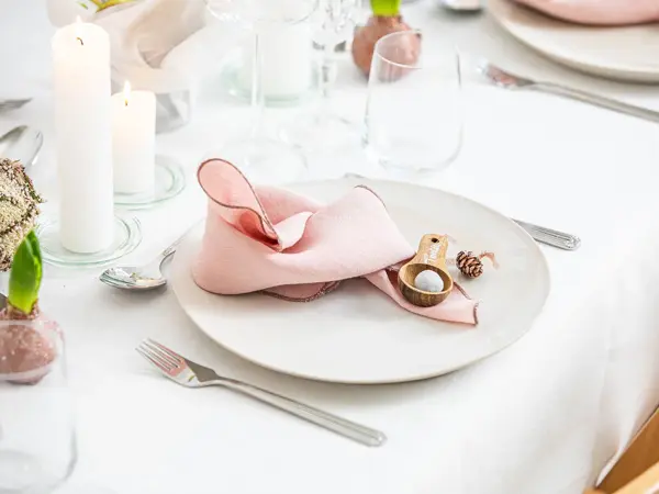 Langbord dekker til gjester med rosa servietter og grønn naturlig dekorasjon