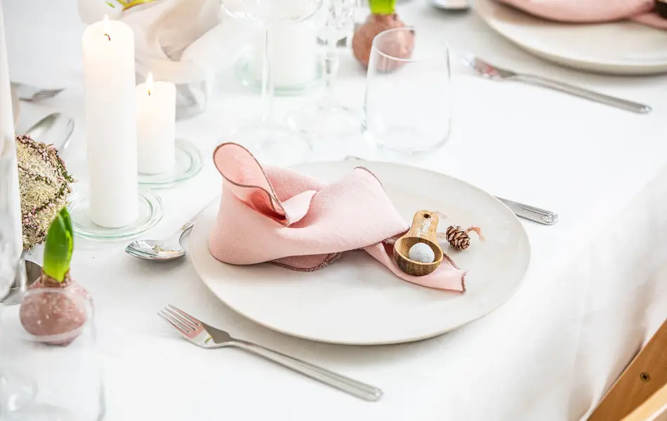 Langbord dekker til gjester med rosa servietter og grønn naturlig dekorasjon