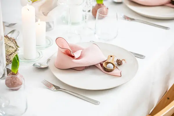 Langbord dekker til gjester med rosa servietter og grønn naturlig dekorasjon