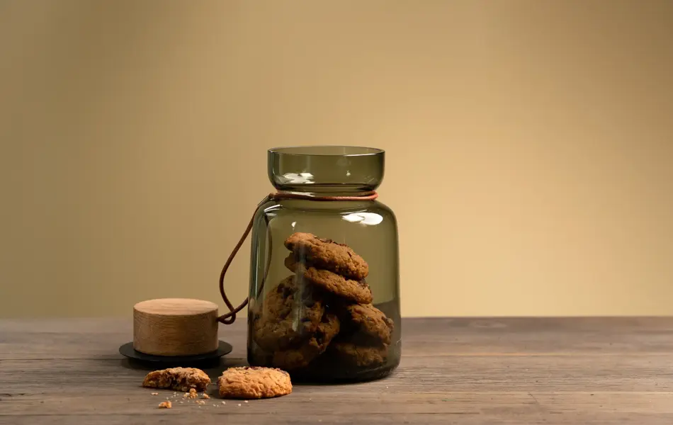 En dame som holder på med oppussing og tips om interiør trender for våren 2021. Damen har lyst halvlangt hå og har på seg en blå olaskjorte og blå olabukse. Fargene går i brunt og beige jordtoner og det er mye lilla og pastellfarger. Vårens interiør