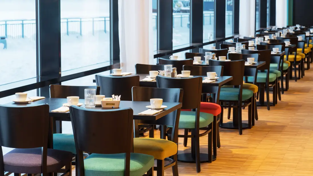Bord i frokostsal med store vinduer som gir utsikt mot kaia og havet på Thon Hotel Kirkenes ved kaia i Kirkenes sentrum