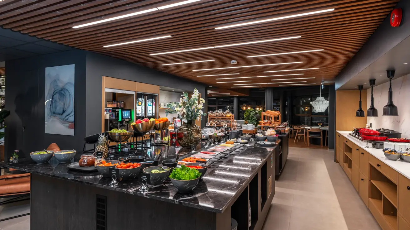 Frokostbuffet med diverse fargerik oppskåret frukt og grønnsaker, pålegg på små hvite tallerkner.