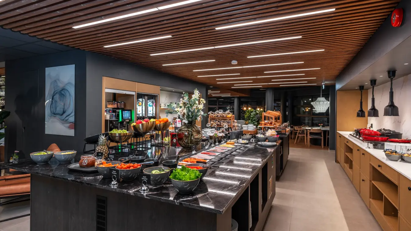 Frokostbuffet med diverse fargerik oppskåret frukt og grønnsaker, pålegg på små hvite tallerkner.