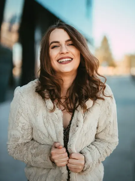 Smilende dame i beige fuskepelsjakke 