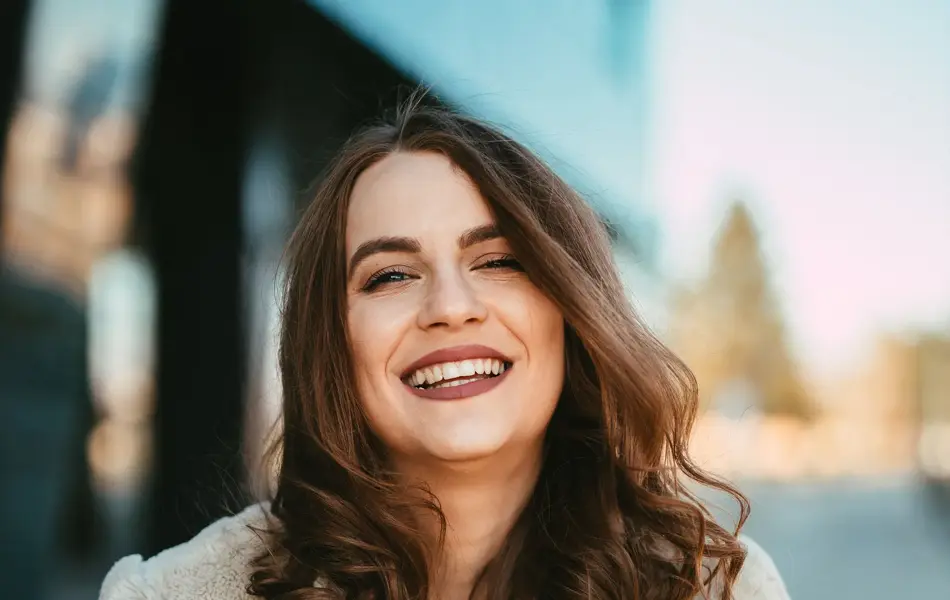 Smilende dame i beige fuskepelsjakke 