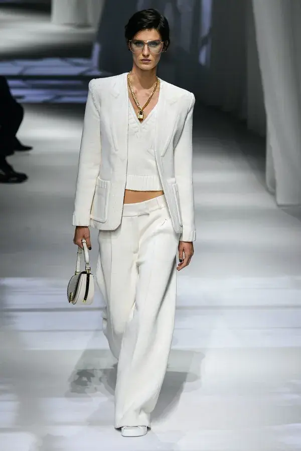 Dame som går på catwalk med hvit dress og hvit topp inni. 