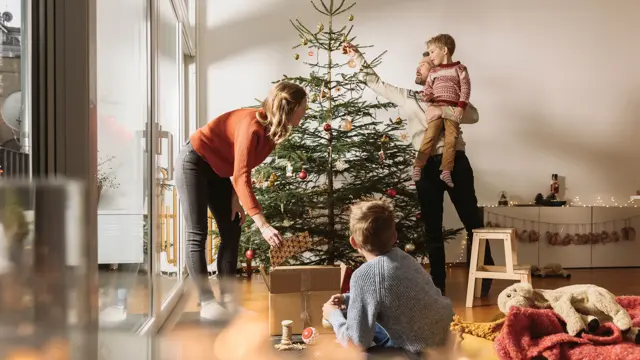 Mor, far og barn pynter juletre