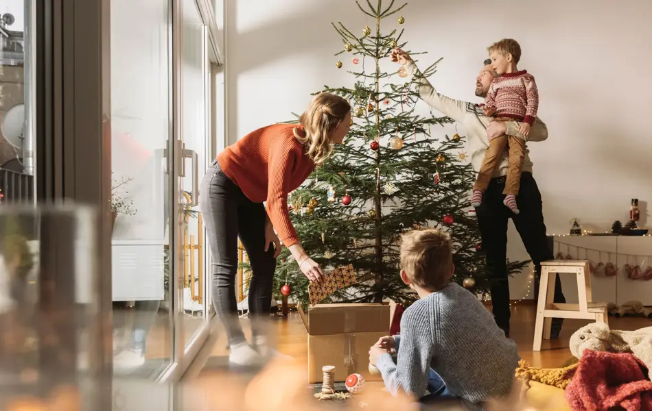 Mor, far og barn pynter juletre