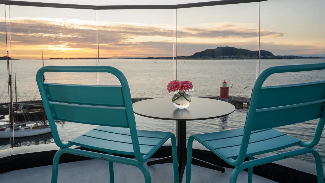 Balkong med utsikt over vannet, to stoler, rundt bord