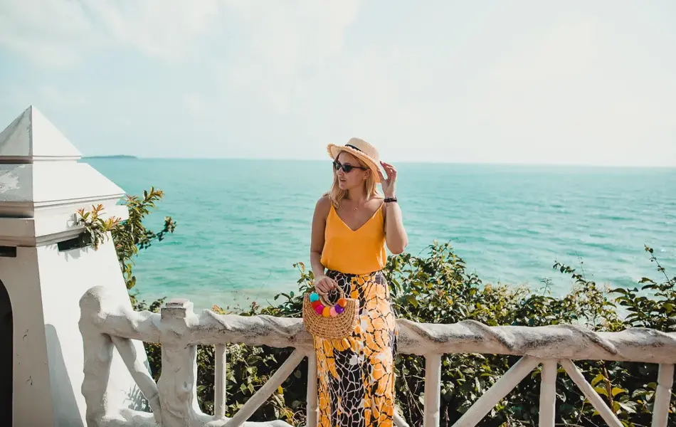 Dame i sommerklær står ved havet