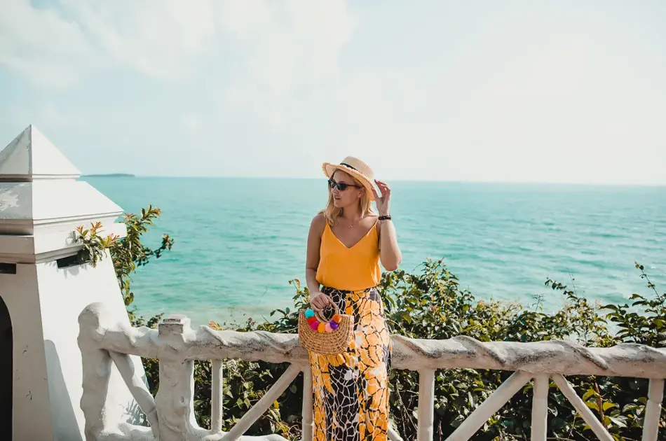 Dame i sommerklær står ved havet