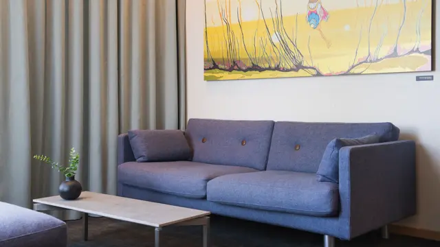 Lille sofa i junior suite, lite sofa bord og stort bilde på veggen.
