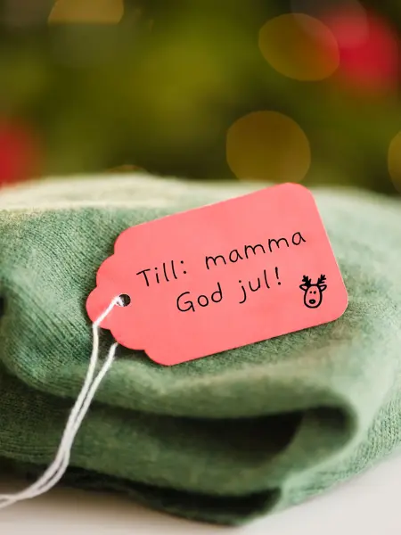 Grønn strikket genser med en rød lapp