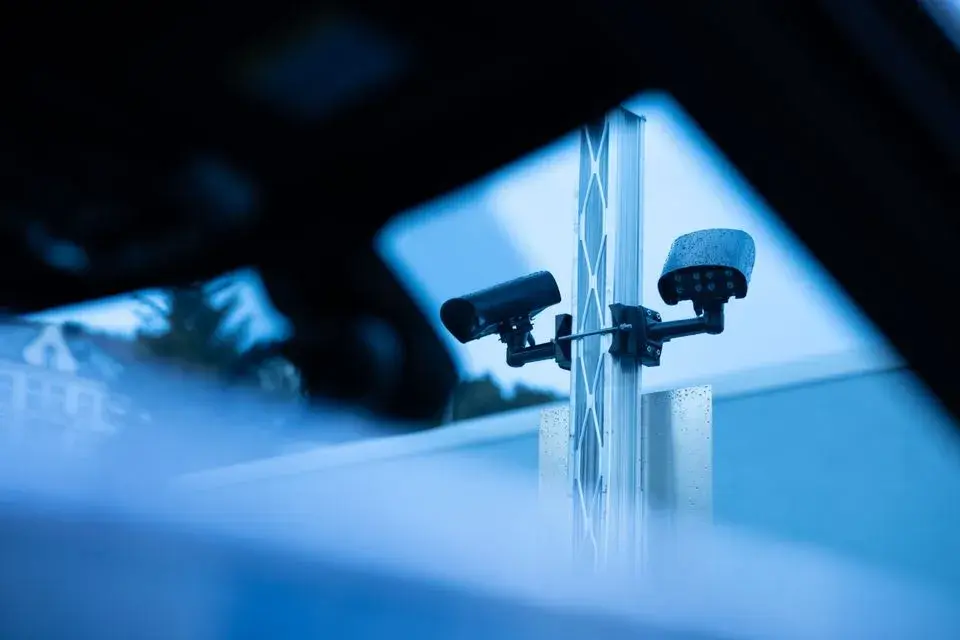 Bilde av kameraer på en stolpe på parkering utendørs