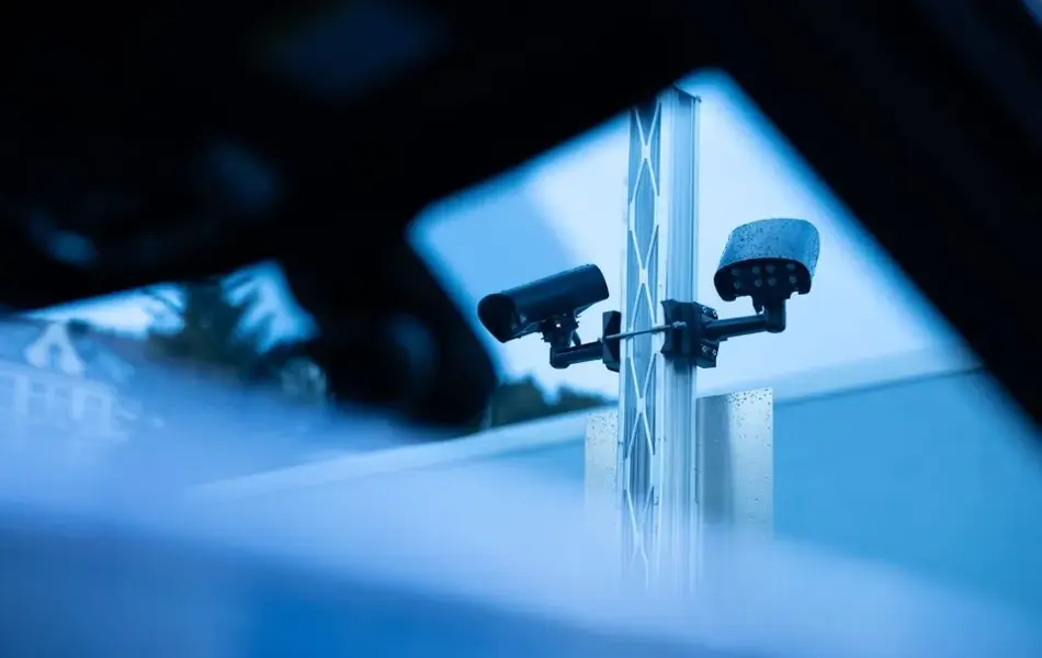 Bilde av kameraer på en stolpe på parkering utendørs