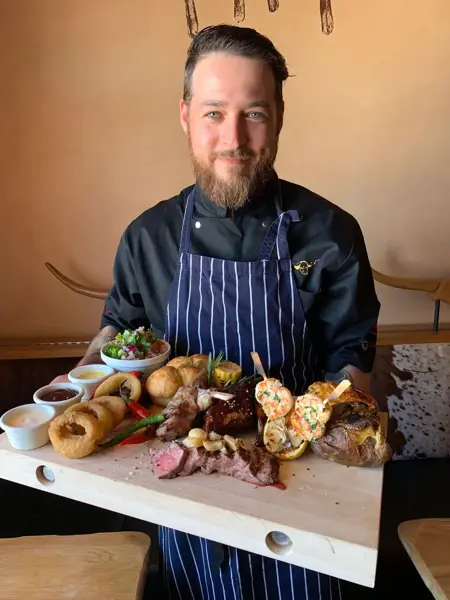 servitør hos Big Horn viser frem dandert mat på serveringsfjøl