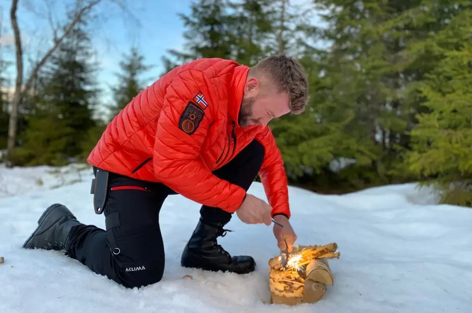mann prøver å få fyr på et bål ute i fri natur