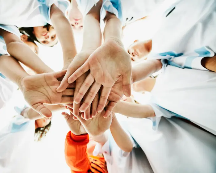 View from below of young female soccer players hands together before game