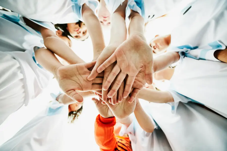 View from below of young female soccer players hands together before game