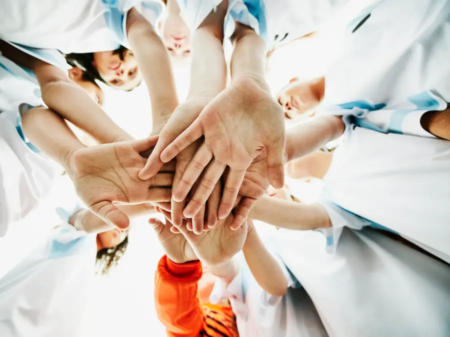 View from below of young female soccer players hands together before game
