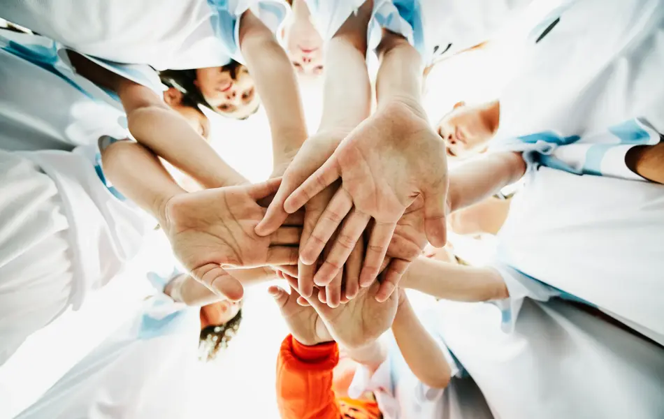 View from below of young female soccer players hands together before game
