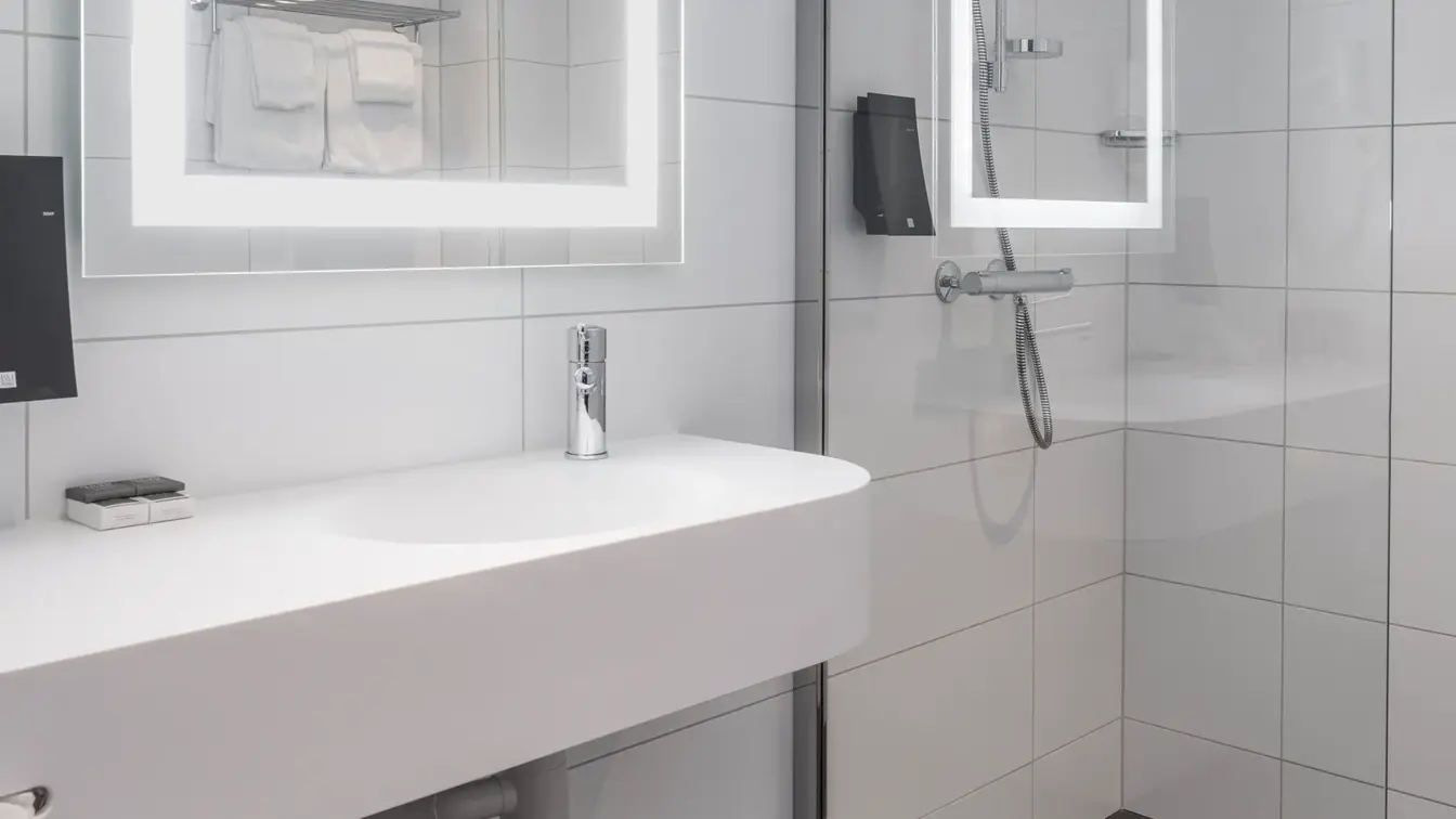 Vask, speil med led lys rundt og dusj på bad i business rom på Thon Hotel Bristol Bergen.