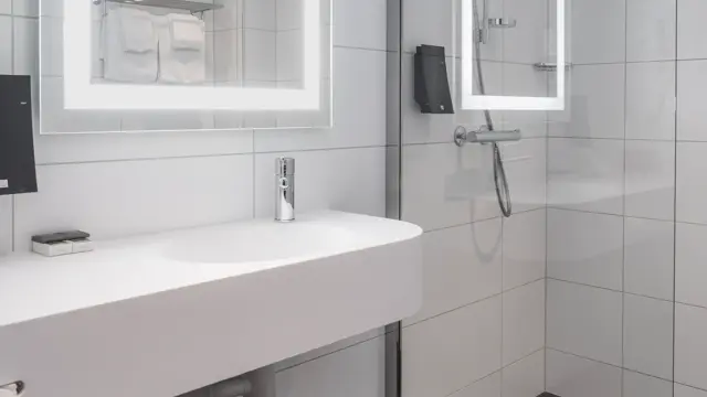 Vask, speil med led lys rundt og dusj på bad i business rom på Thon Hotel Bristol Bergen.