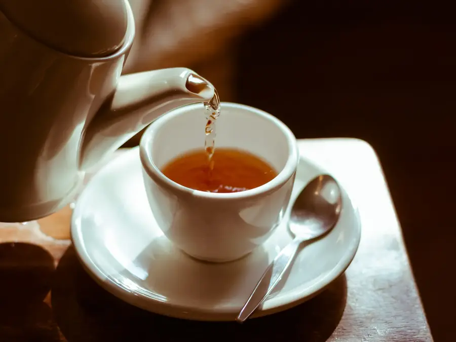 Pouring hot tea into white ceramic tea cup the time of tea break.