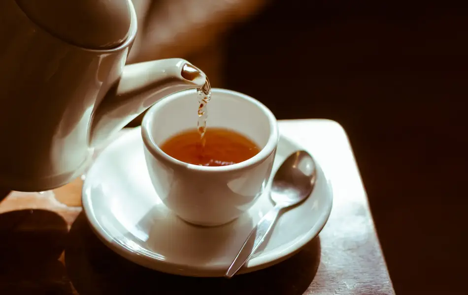 Pouring hot tea into white ceramic tea cup the time of tea break.