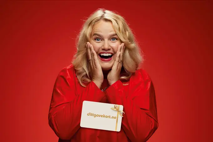 Ung dame som smiler med dittgavekort med juledesign