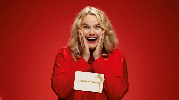 Ung dame som smiler med dittgavekort med juledesign