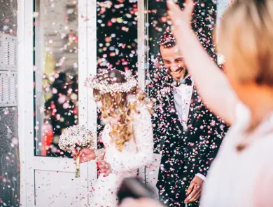 Photo of just married couple. Guests are throwing confetti in the air.