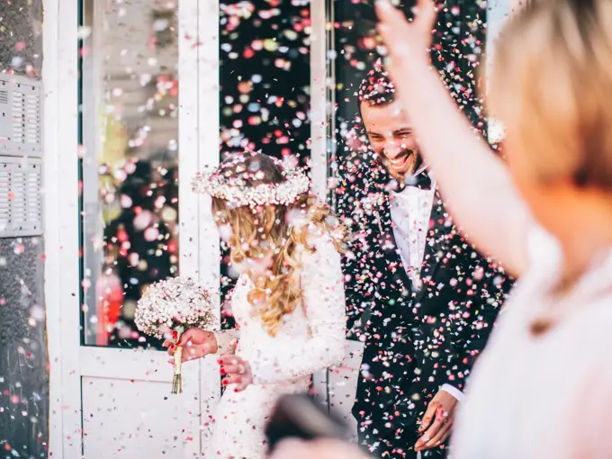 Photo of just married couple. Guests are throwing confetti in the air.