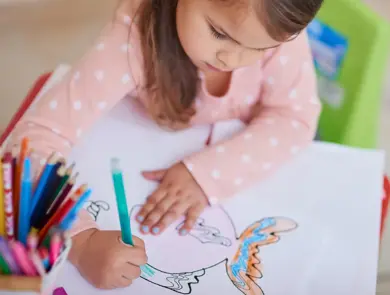 High angle shot of a little girl colouring in a picture at home
