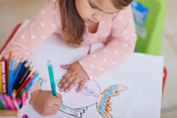 High angle shot of a little girl colouring in a picture at home