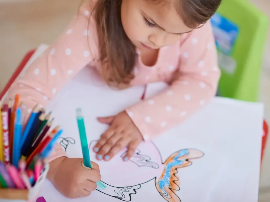 High angle shot of a little girl colouring in a picture at home