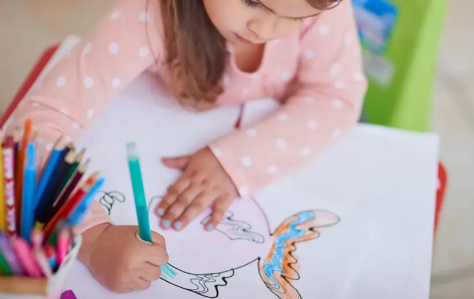 High angle shot of a little girl colouring in a picture at home