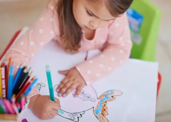 High angle shot of a little girl colouring in a picture at home