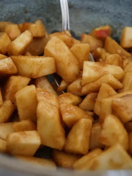 Bolle med eplebiter som er rørt inn med brunt sukker