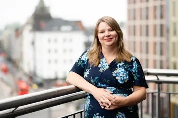 Portrett av Anna Marie Fjeld. Hun står foran et gjerde. 