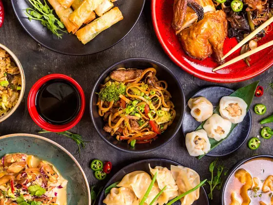 diverse asiatiske matretter og saus omringet av chili og andre grønnsaker