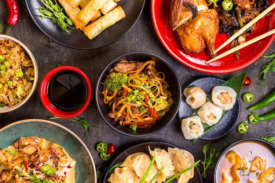 diverse asiatiske matretter og saus omringet av chili og andre grønnsaker